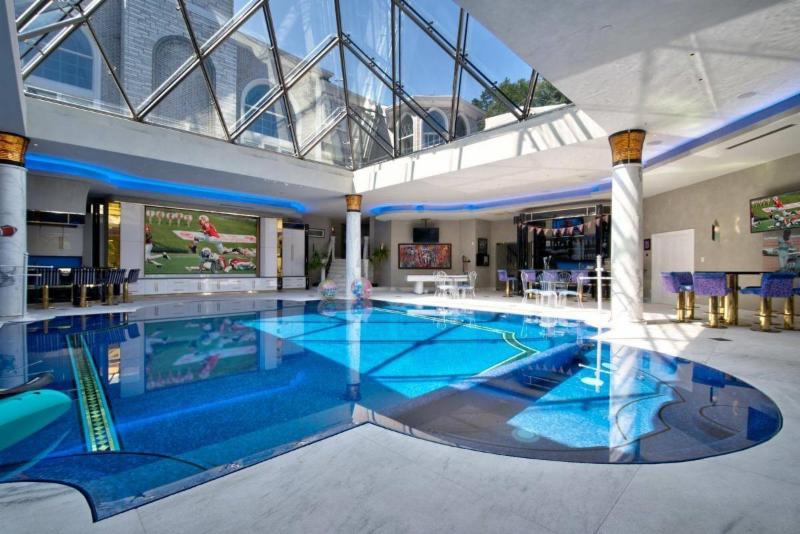 Indoor swimming pool beneath skylight designed like the pyramid at The Louvre.