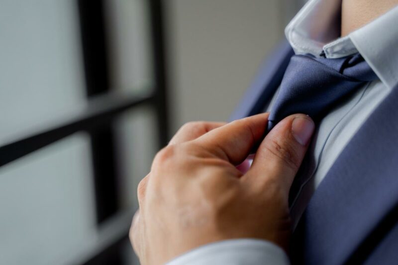 Hand straightening tie of a professional male, presumably a forensic engineer.